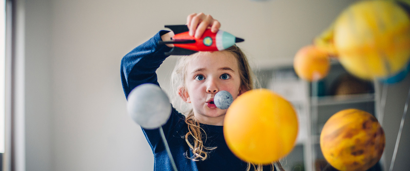 Kind spielt mit Rakete vor Planetenmodell